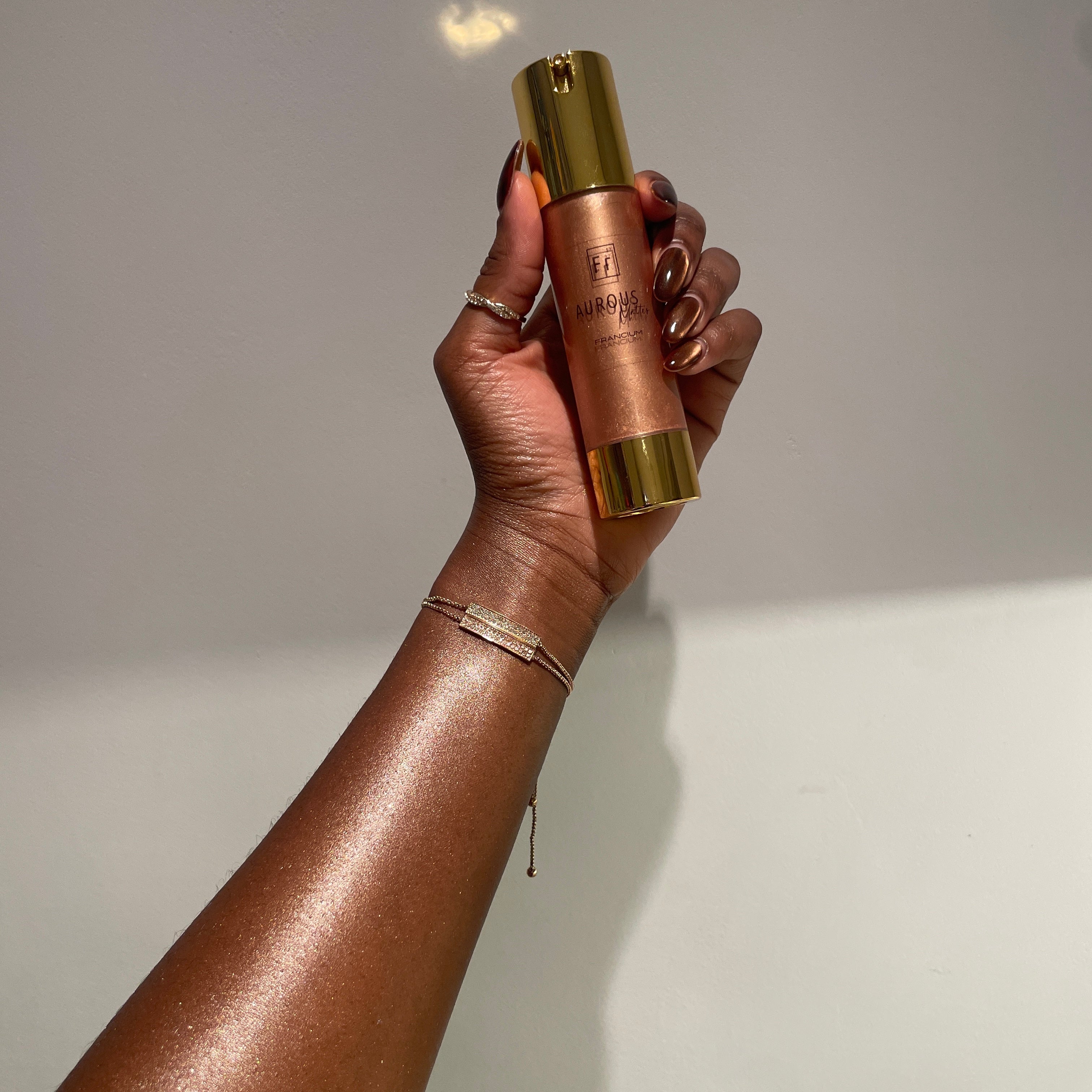 image of aurous bronzer in shade francium on the skin with 50ml product in hand.