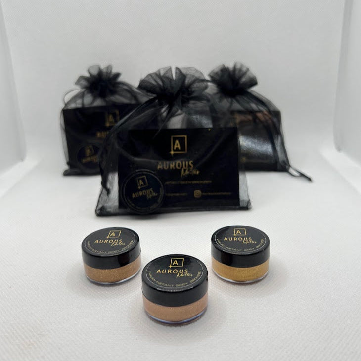 Three small jars of cosmetic product with black lids on a white surface, surrounded by black drawstring bags.