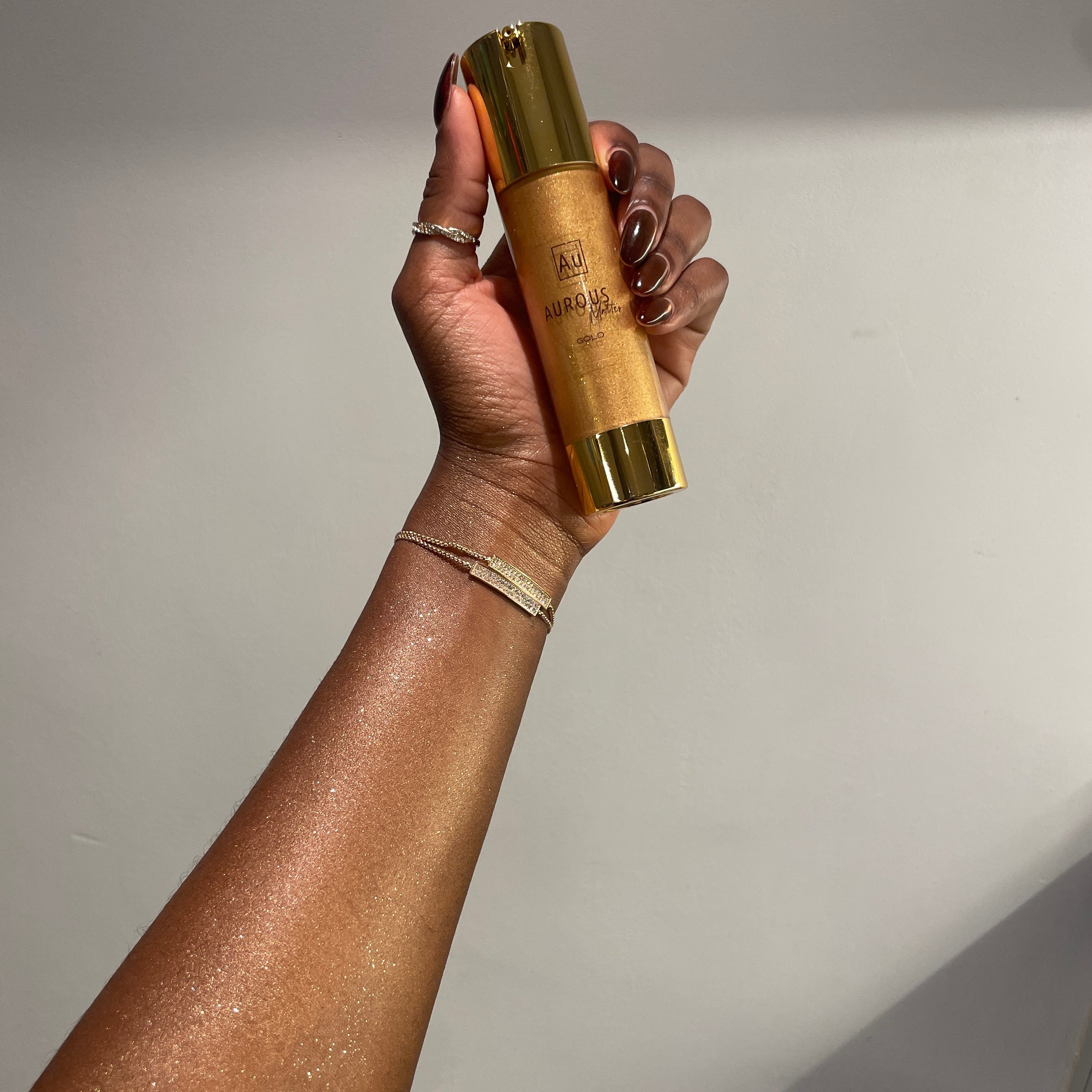 image of aurous bronzer in shade gold on the skin with 50ml product in hand.
